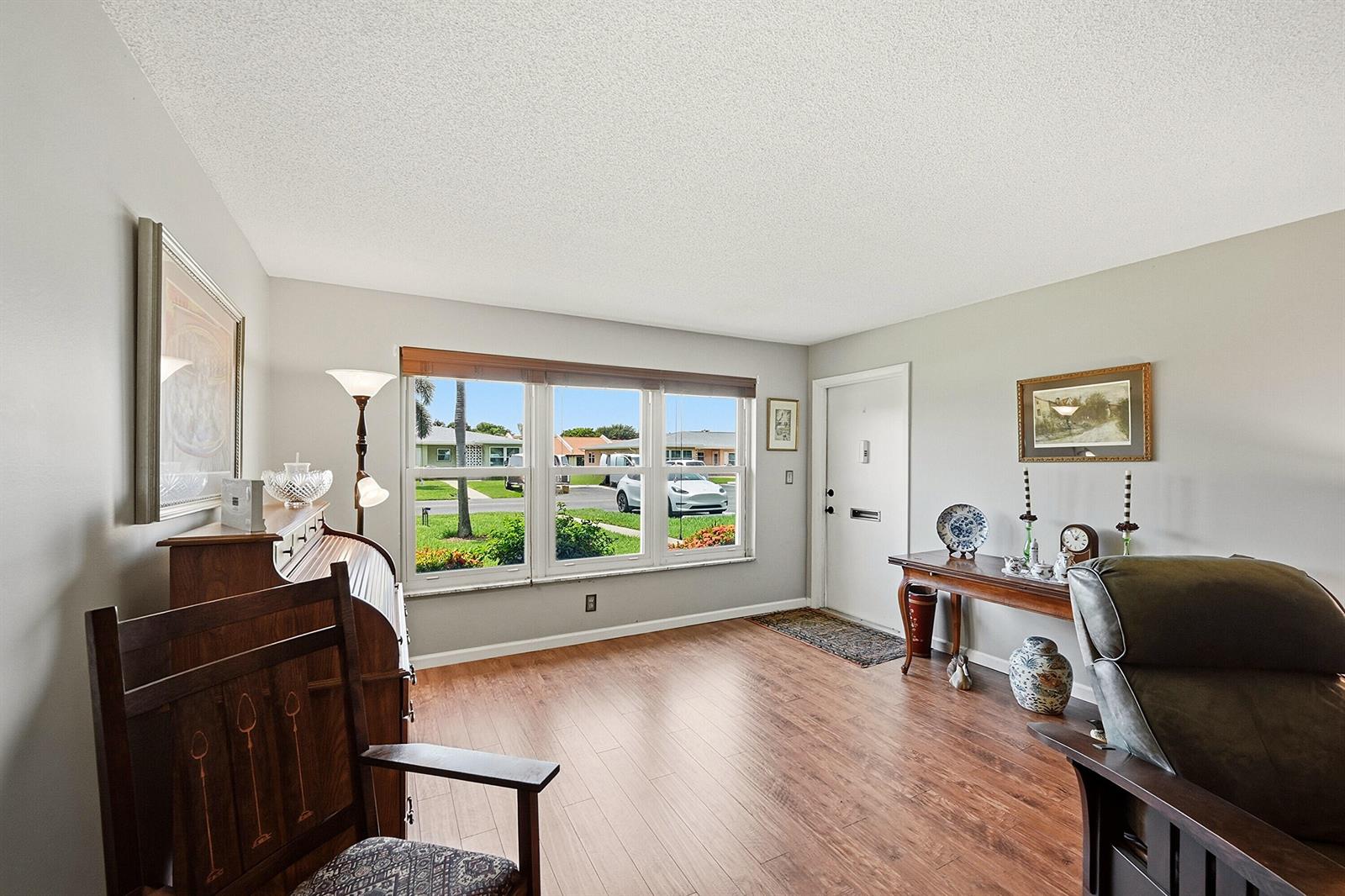 A living room features wood-look flooring, a large window, and a white front door — 295 High Point Boulevard # B, Boynton Beach FL 33435, BOYNTON BEACH, FL