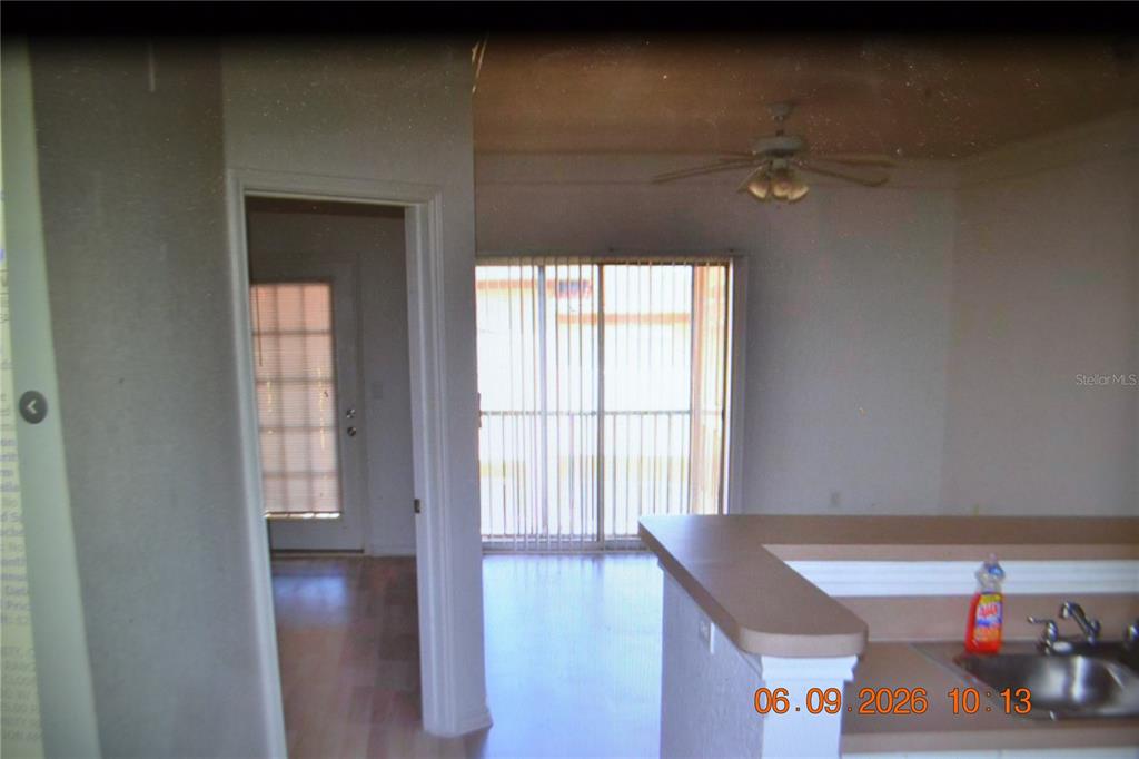 A kitchen counter overlooks a living area with a ceiling fan and sliding glass doors — 4323 BAYSIDE VILLAGE DRIVE UNIT 206, TAMPA, FL