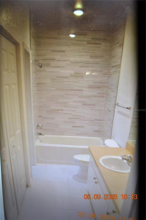 A bathroom features a tub-shower combination with horizontal tiled walls, a vanity, and a toilet — 4323 BAYSIDE VILLAGE DRIVE UNIT 206, TAMPA, FL