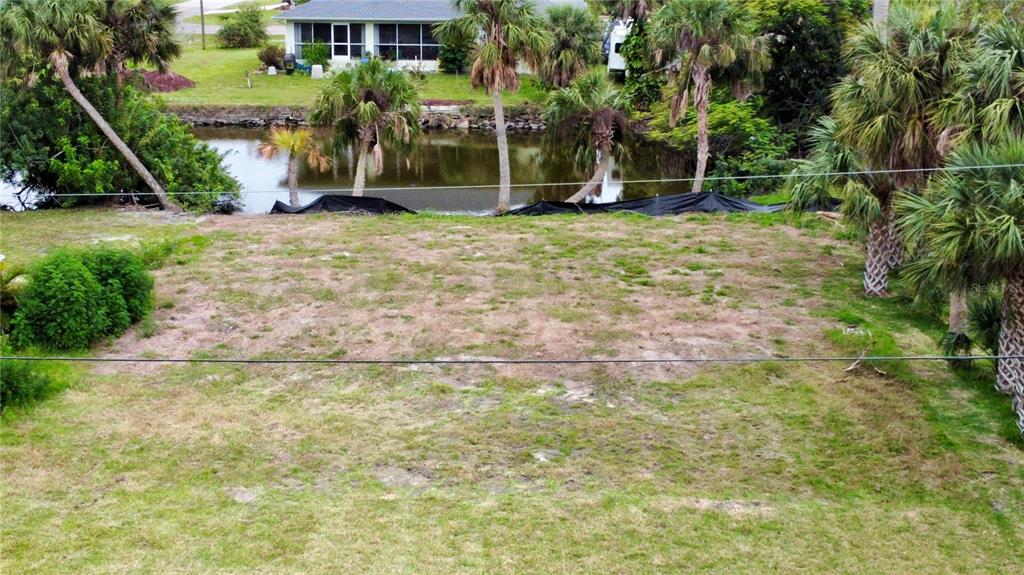 An elevated view of a vacant, grassy lot bordering a canal with palm trees — 341 LAKE COURT, PUNTA GORDA, FL