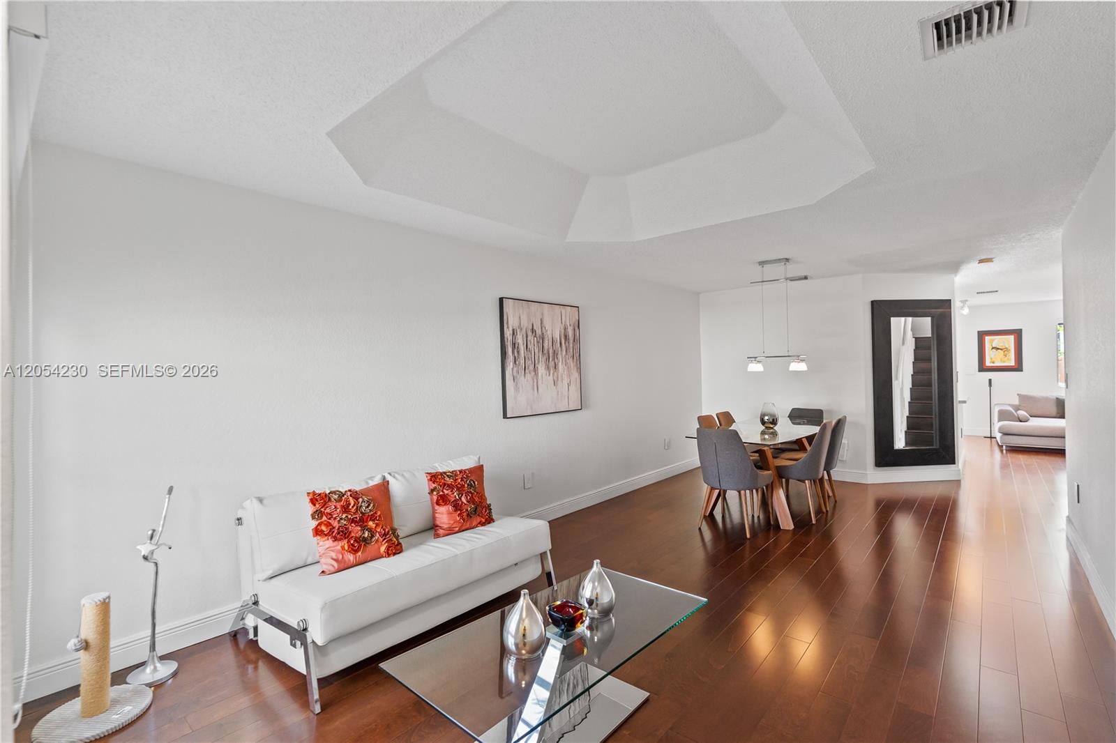 A living and dining room area features white walls, dark wood floors, and a tray ceiling — 5115 NW 116th Ave, Doral FL 33178, DORAL, FL