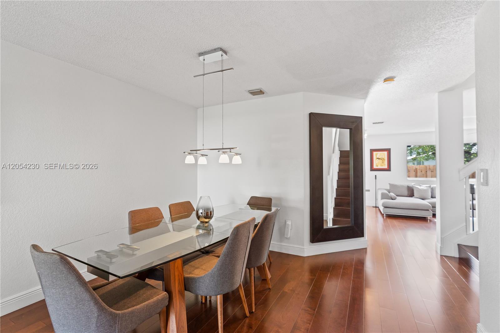 A dining room features a glass-topped table, gray upholstered chairs, and wood flooring — 5115 NW 116th Ave, Doral FL 33178, DORAL, FL
