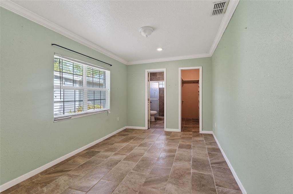 A bedroom with light green walls, tile flooring, a window, and two doorways — 540 W COLUMBIA STREET, LAKE ALFRED, FL