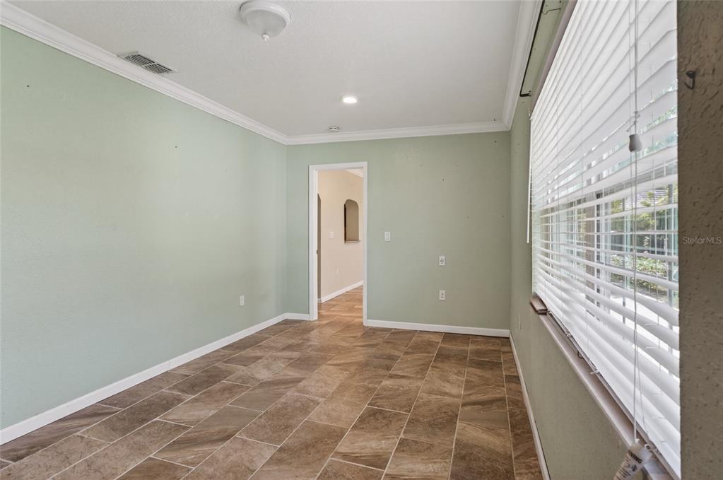An empty room with light green walls, tile flooring, and a window with white blinds — 540 W COLUMBIA STREET, LAKE ALFRED, FL