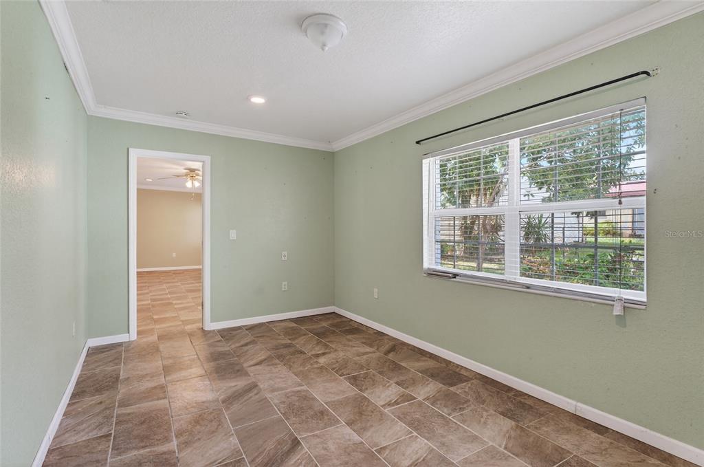 An empty room with sage green walls, tile flooring, and a large window — 540 W COLUMBIA STREET, LAKE ALFRED, FL
