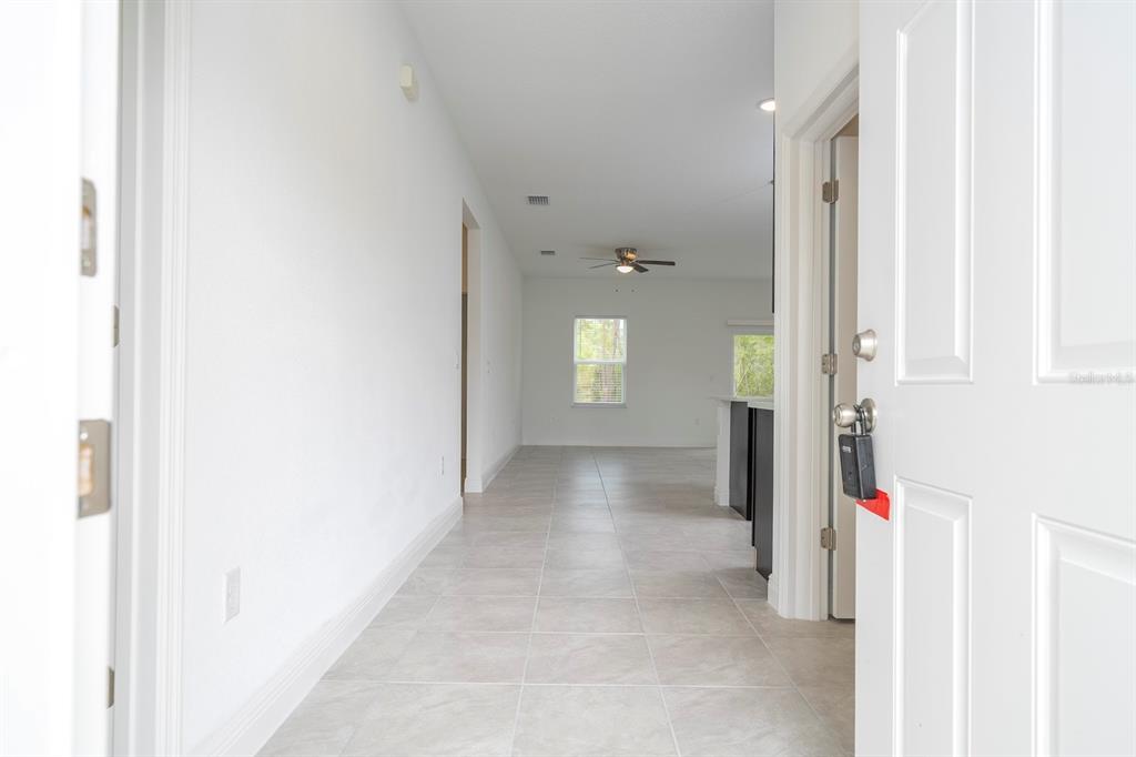 A view from a doorway looking down a tiled hallway into an open living area — 5146 SW 158TH STREET, OCALA, FL