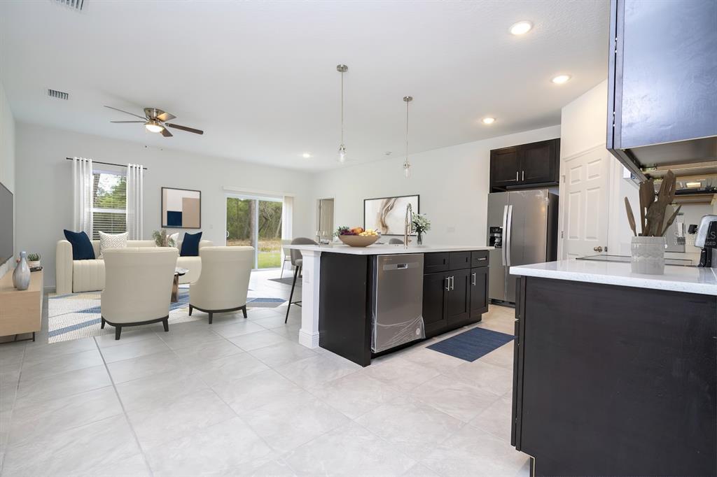 An open-concept kitchen and living area featuring dark cabinetry, stainless appliances, and tile flooring — 5146 SW 158TH STREET, OCALA, FL