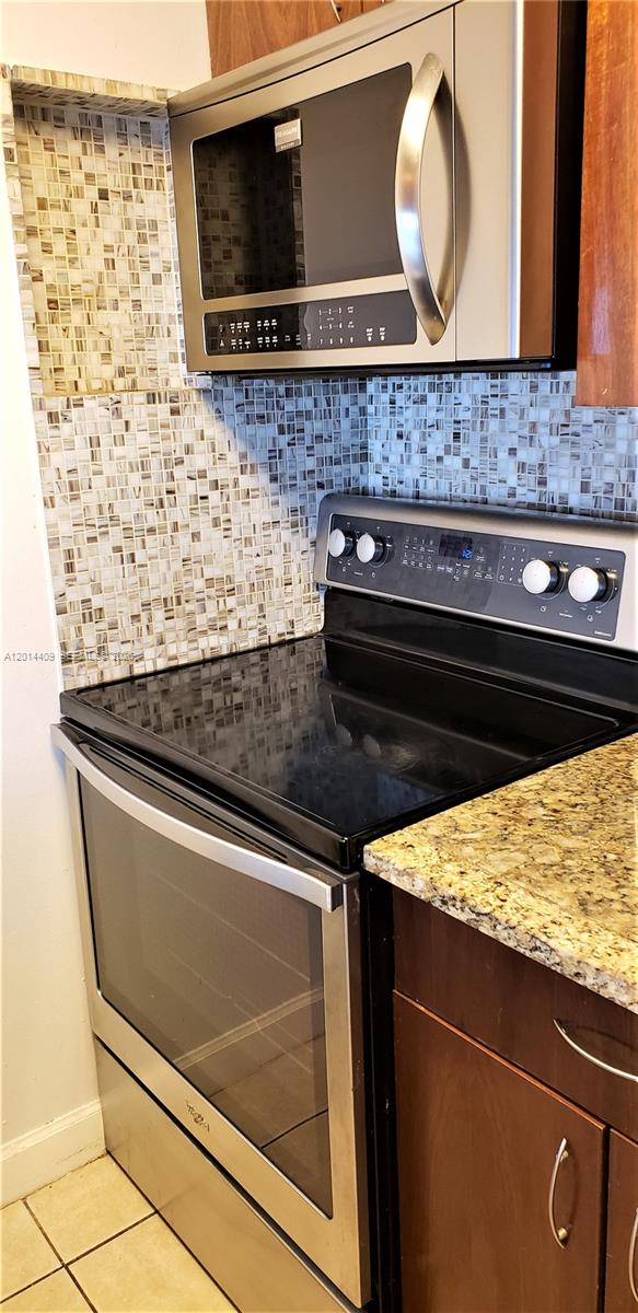 A kitchen features a stainless steel oven, microwave, granite countertop, and a tiled backsplash — 850 N Miami Ave # 903, Miami FL 33136, MIAMI, FL