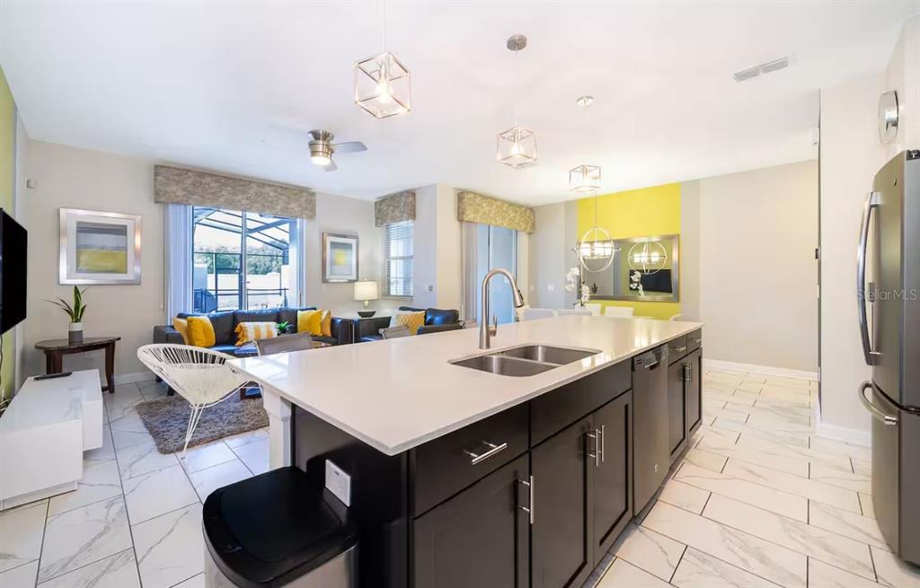 A kitchen island with a sink sits in front of a living area with tiled floors — 4909 WINDERMERE AVENUE, KISSIMMEE, FL