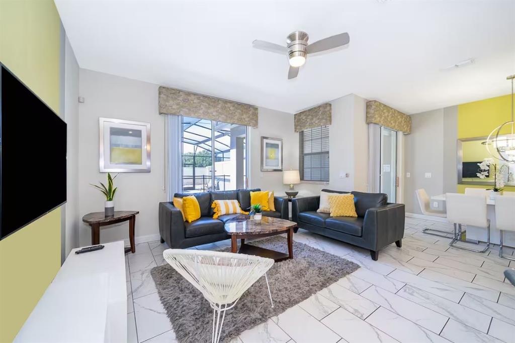 A living room features dark leather sofas, a marble coffee table, and white tile flooring — 4909 WINDERMERE AVENUE, KISSIMMEE, FL