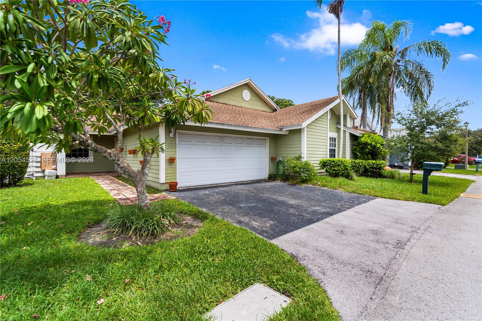 A light green single-story house features a two-car garage, a paved walkway, and palm trees — 10344 SW 141st Ct, Miami FL 33186, MIAMI, FL