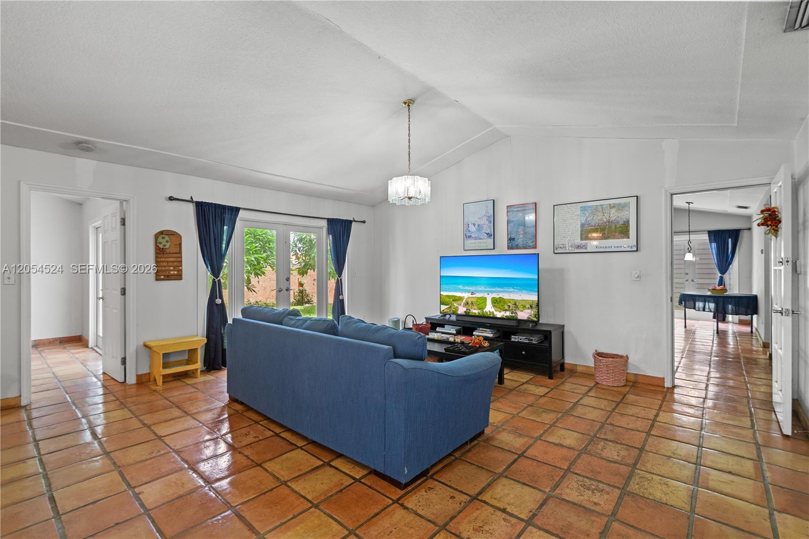 A living room features a blue sofa, tile flooring, a television, and a vaulted ceiling — 10344 SW 141st Ct, Miami FL 33186, MIAMI, FL