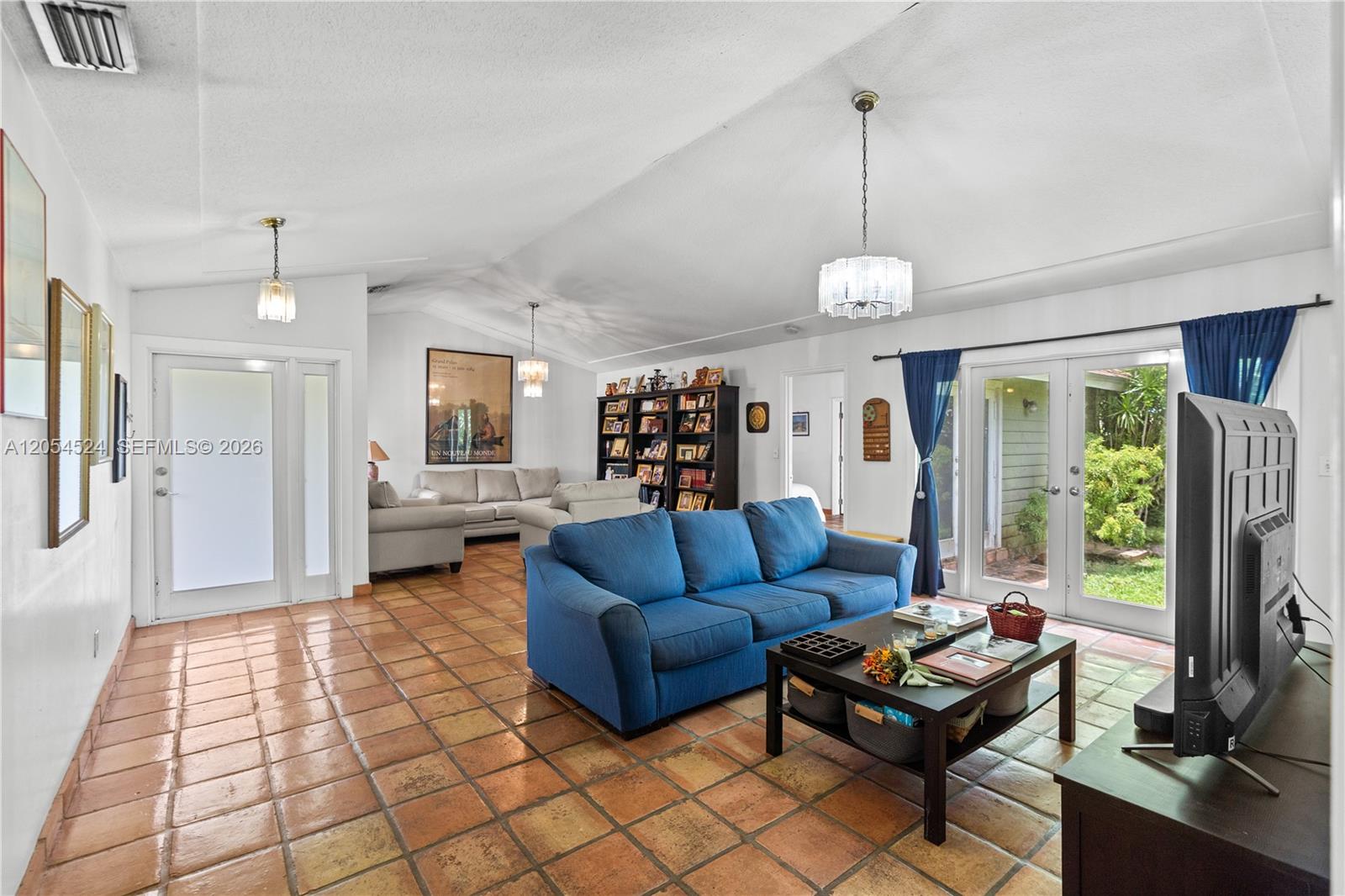 A living room features a blue sofa, tile flooring, a vaulted ceiling, and glass doors — 10344 SW 141st Ct, Miami FL 33186, MIAMI, FL