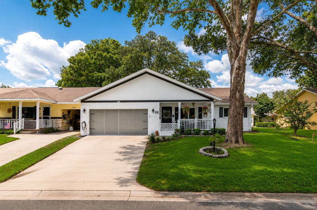 A white single-story house with a two-car garage, front porch, and a large shade tree — 8876 SW 95TH LANE UNIT E, OCALA, FL