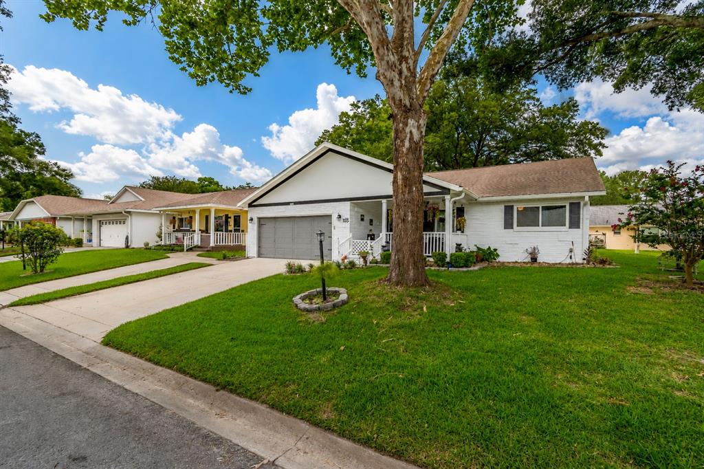 A white single-story house with a gray garage and a large tree in the yard — 8876 SW 95TH LANE UNIT E, OCALA, FL