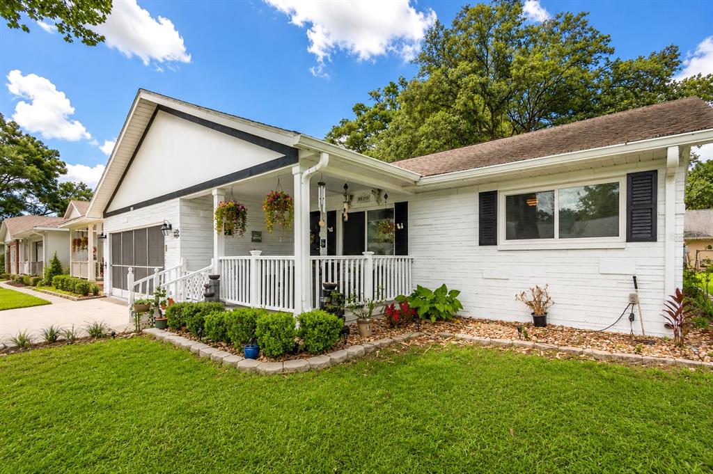 A white brick house features a covered front porch, black shutters, and a manicured lawn — 8876 SW 95TH LANE UNIT E, OCALA, FL