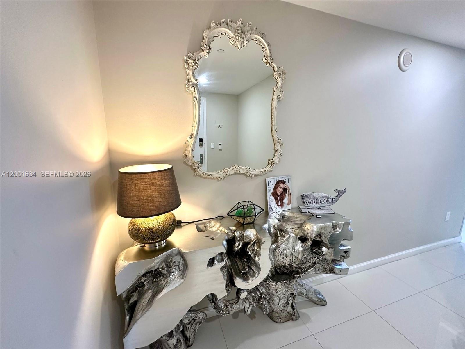 A silver driftwood console table sits beneath an ornate mirror in a modern entryway — 485 Brickell Ave # 4408, Miami FL 33131, MIAMI, FL