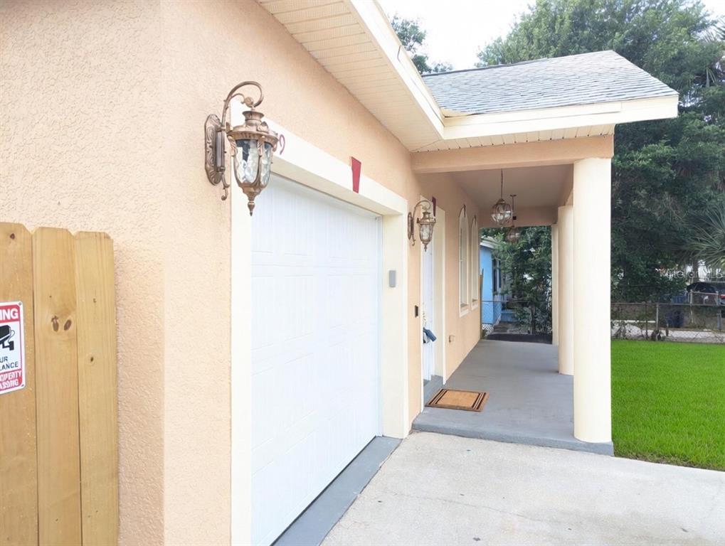 A beige house exterior features a white garage door, a covered porch, and two lanterns — 3809 N WHITTIER STREET, TAMPA, FL
