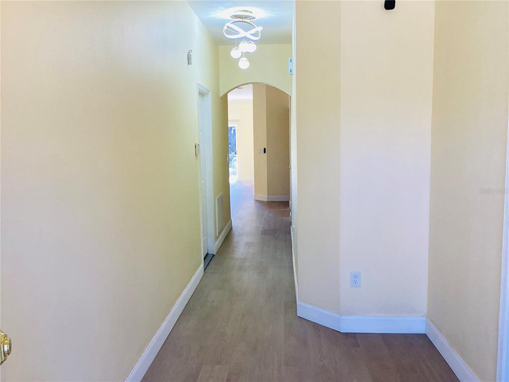 A hallway with light yellow walls, wood-look flooring, and an arched entryway — 3809 N WHITTIER STREET, TAMPA, FL