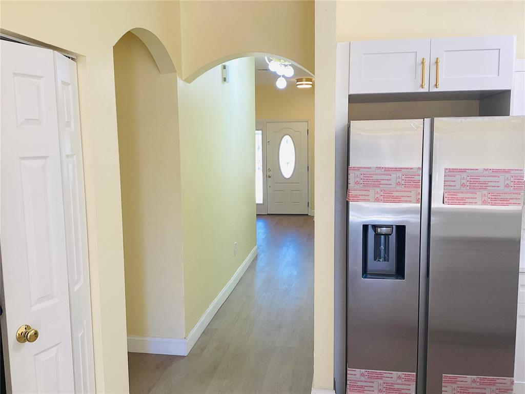 A view from a kitchen toward a hallway with an arched entryway and front door — 3809 N WHITTIER STREET, TAMPA, FL