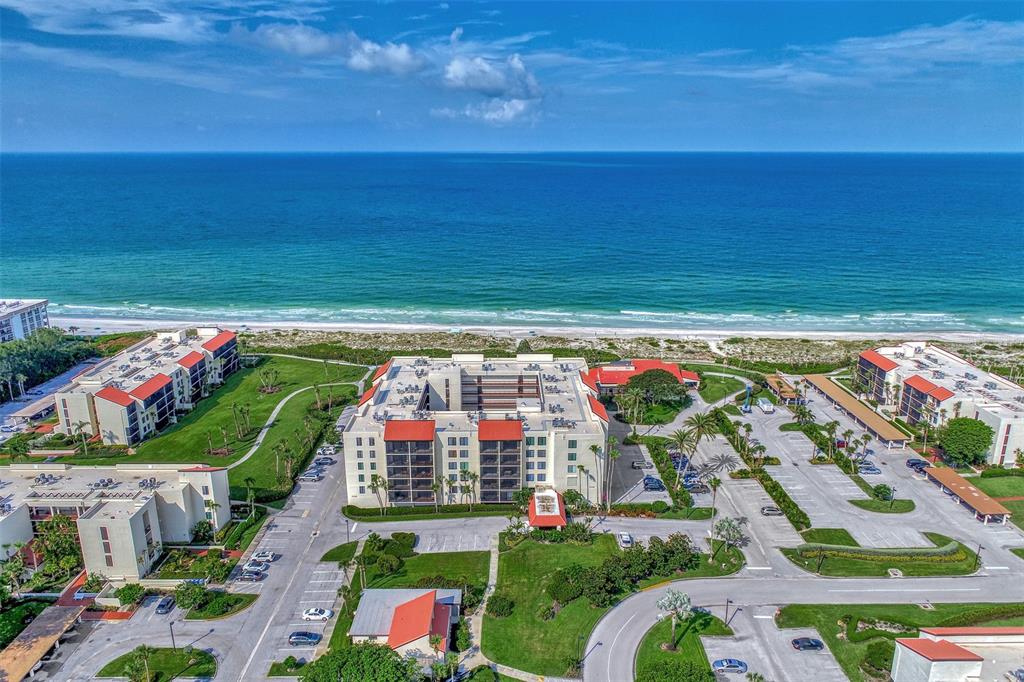 An aerial view shows a multi-story beachfront resort complex with parking lots and green lawns — 1945 GULF OF MEXICO DRIVE UNIT M2-414, LONGBOAT KEY, FL