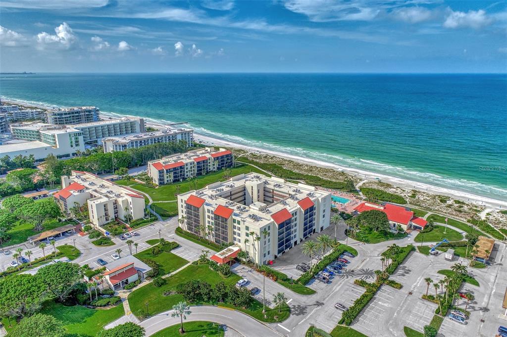 An aerial view of beachfront condominium buildings surrounded by parking lots and green lawns — 1945 GULF OF MEXICO DRIVE UNIT M2-414, LONGBOAT KEY, FL
