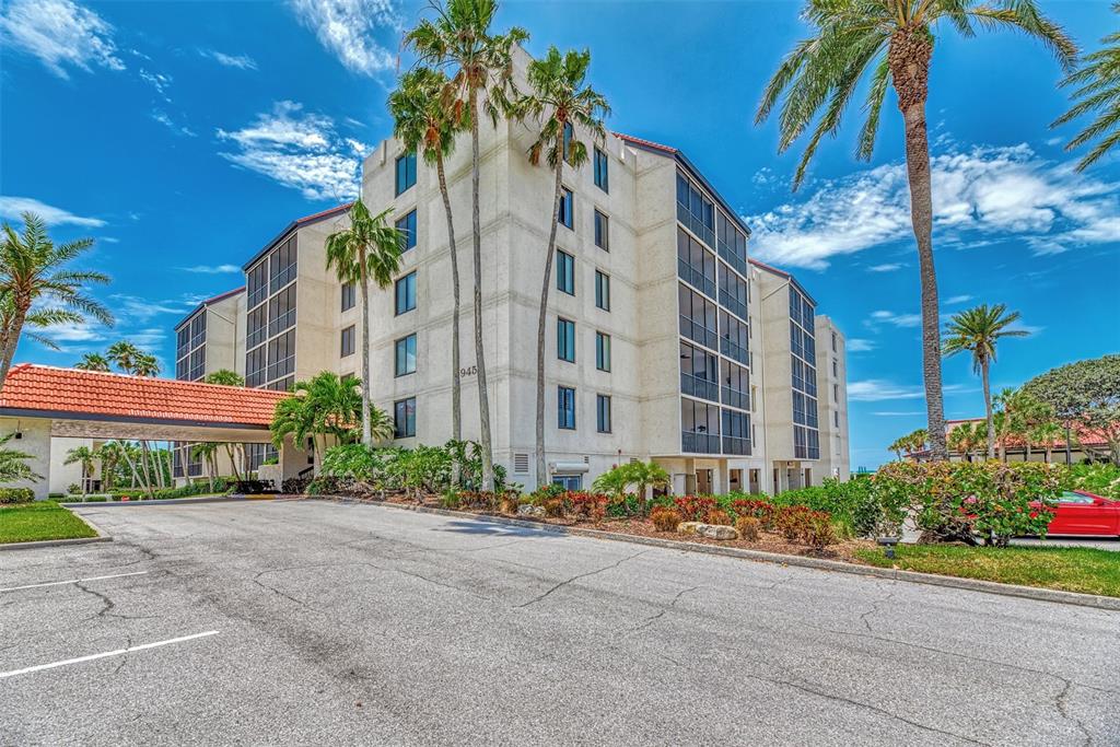 A multi-story beige apartment building with a red tile roof and palm trees outside — 1945 GULF OF MEXICO DRIVE UNIT M2-414, LONGBOAT KEY, FL
