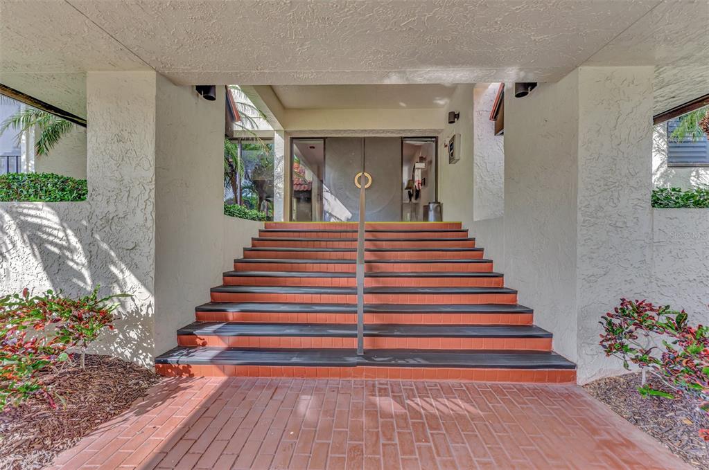 A set of brick stairs with a central handrail leads to a double-door building entrance — 1945 GULF OF MEXICO DRIVE UNIT M2-414, LONGBOAT KEY, FL