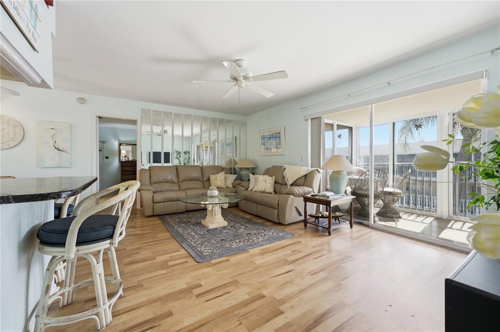 A living room with light wood floors, a beige sectional, and a glass sliding door — 3755 S SCHOOL AVENUE UNIT 41, SARASOTA, FL