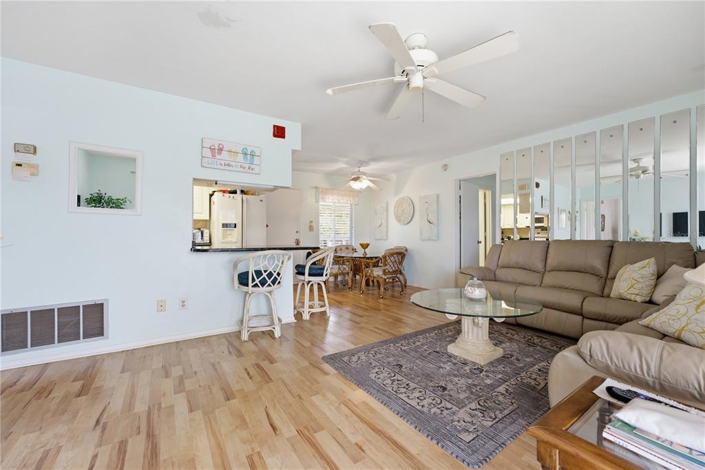 A living room with light wood floors, a beige sofa, and a kitchen pass-through window — 3755 S SCHOOL AVENUE UNIT 41, SARASOTA, FL