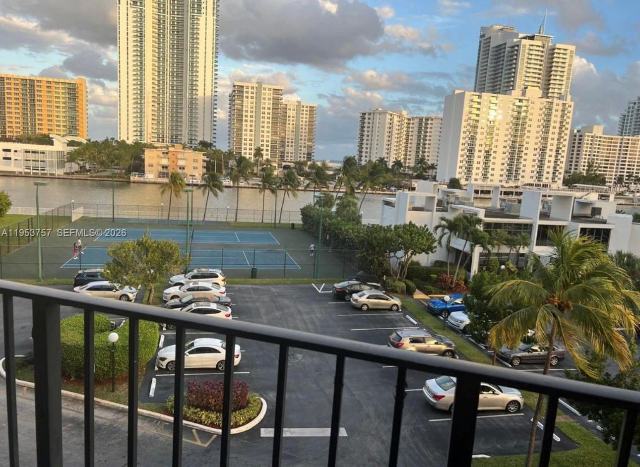 An elevated view of a parking lot, tennis courts, and a waterway surrounded by high-rise buildings — 1000 Parkview Dr # 528, Hallandale Beach FL 33009, HALLANDALE BEACH, FL