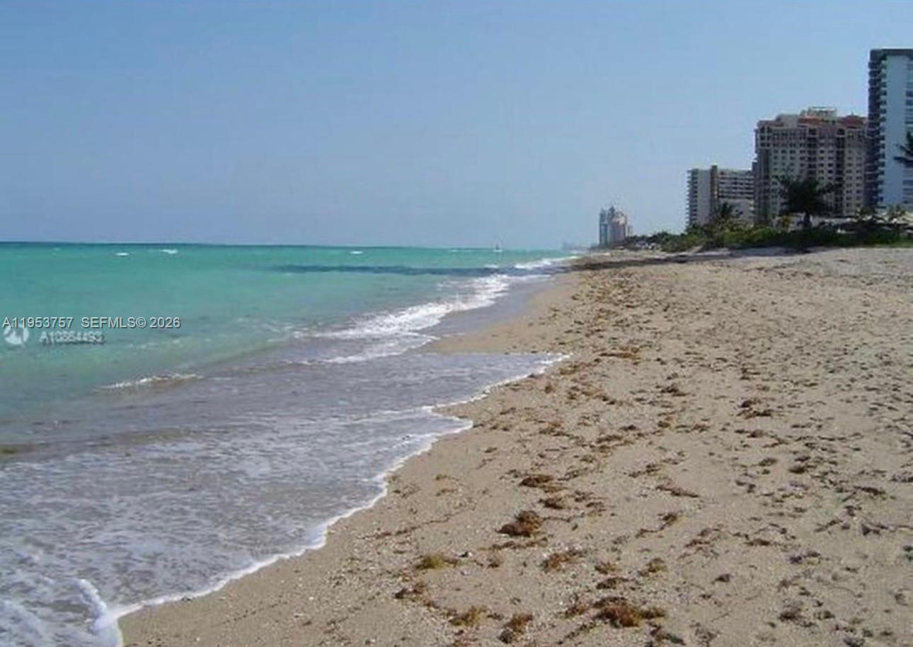 A sandy beach stretches along the turquoise ocean with high-rise buildings in the background — 1000 Parkview Dr # 528, Hallandale Beach FL 33009, HALLANDALE BEACH, FL