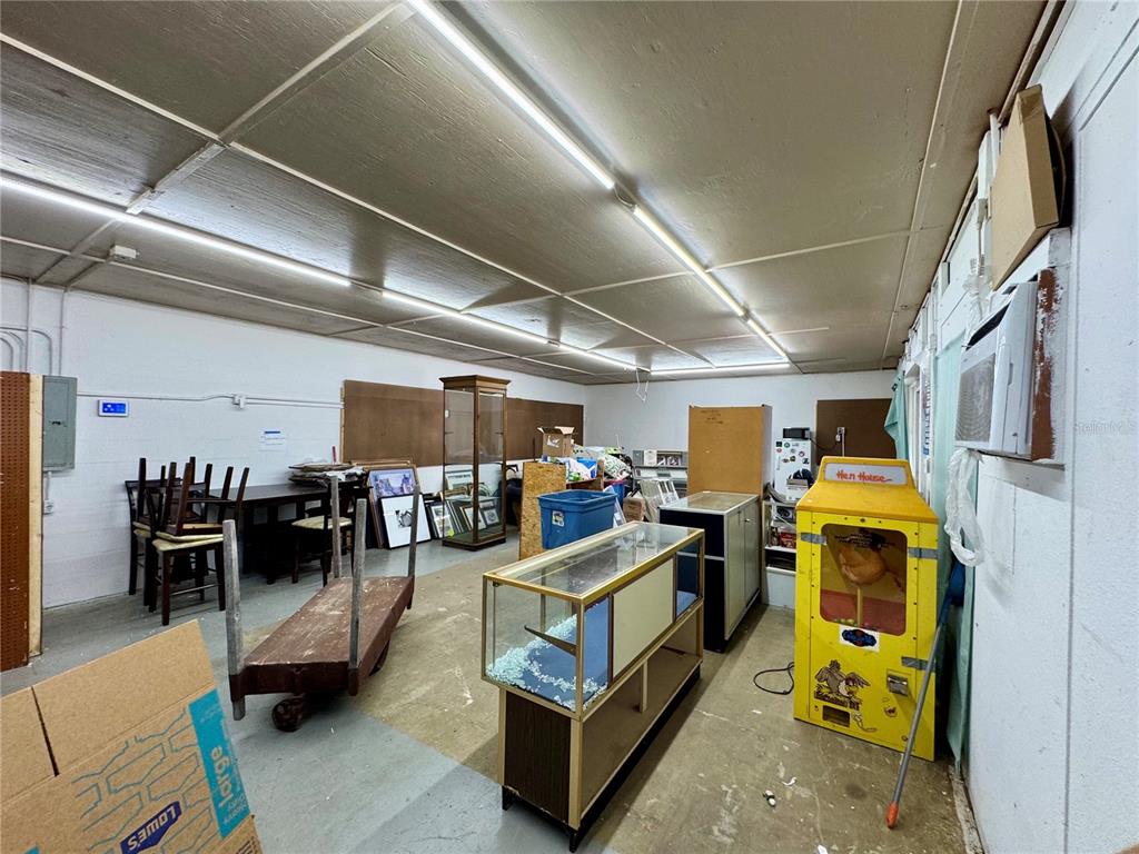 A cluttered storage room features fluorescent ceiling lights, concrete floors, and various display cases — 6221 SE 110TH STREET, BELLEVIEW, FL
