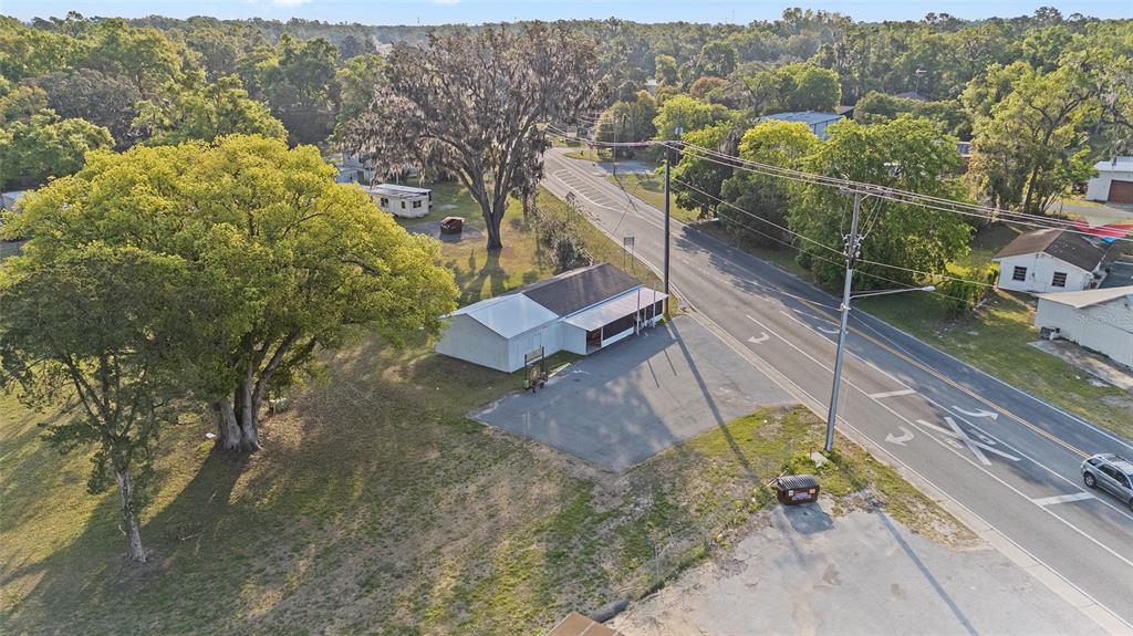 An aerial view shows a small white building with a metal roof beside a road — 6221 SE 110TH STREET, BELLEVIEW, FL