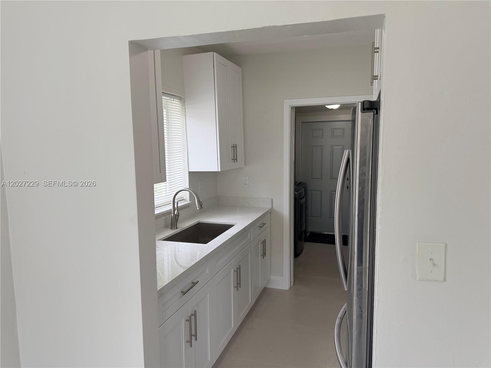 A kitchen features white cabinets, a stainless steel sink, and a stainless steel refrigerator — 1185 NW 100th St # 1185, Miami FL 33150, MIAMI, FL