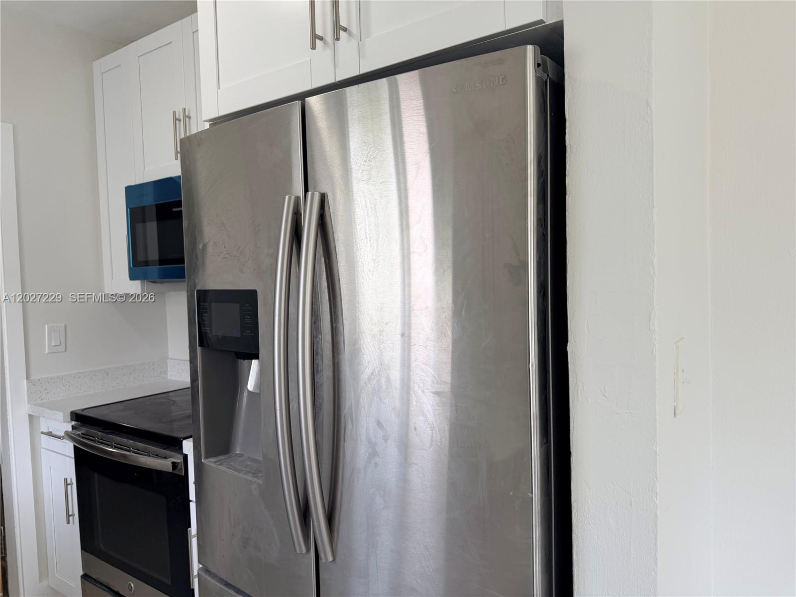 A stainless steel Samsung refrigerator is positioned in a kitchen with white cabinets — 1185 NW 100th St # 1185, Miami FL 33150, MIAMI, FL