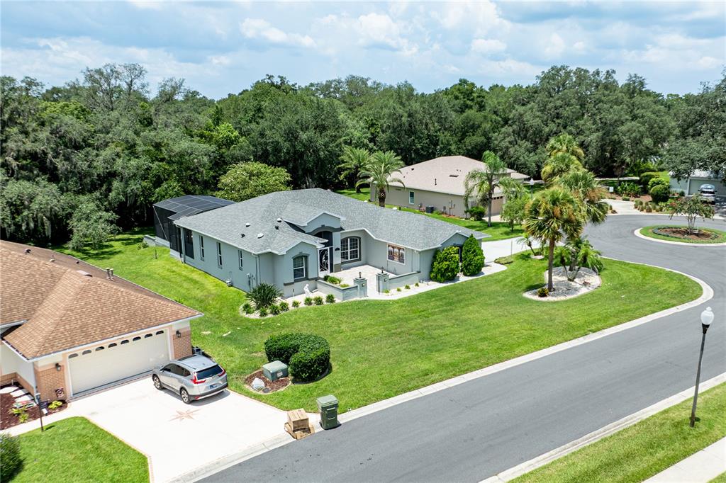 An aerial view shows a light-colored single-story house with a gray roof and pool enclosure — 5121 AURORA DRIVE, LEESBURG, FL