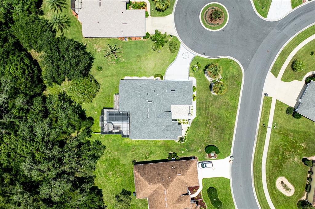 An aerial view shows a residential house with a screened pool and surrounding green lawn — 5121 AURORA DRIVE, LEESBURG, FL