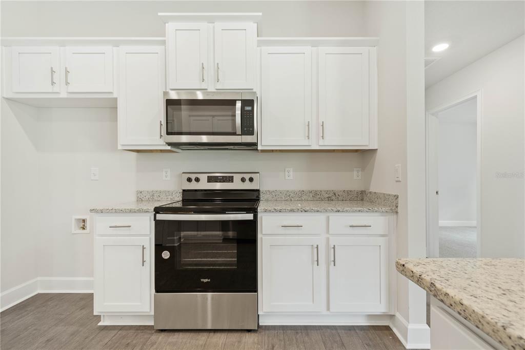 A kitchen features white cabinets, granite countertops, and stainless steel appliances — 338 UNDERWOOD TRAIL, PALM COAST, FL