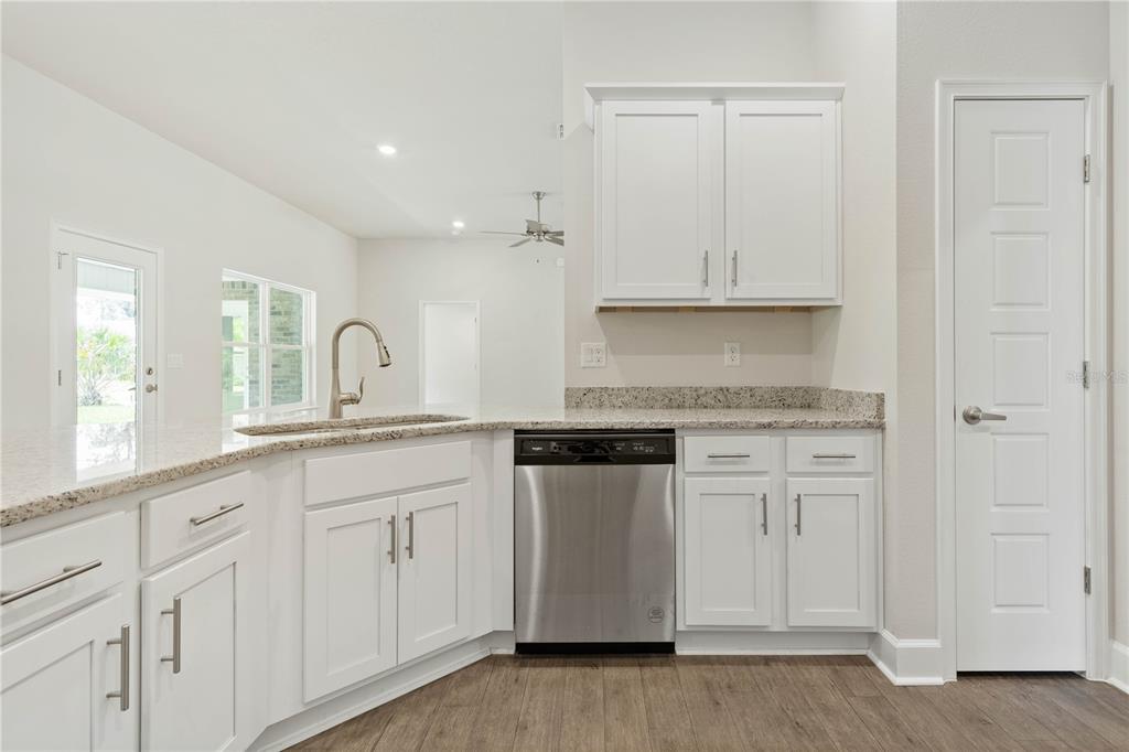 A kitchen features white cabinets, granite countertops, stainless steel appliances, and wood-look flooring — 338 UNDERWOOD TRAIL, PALM COAST, FL
