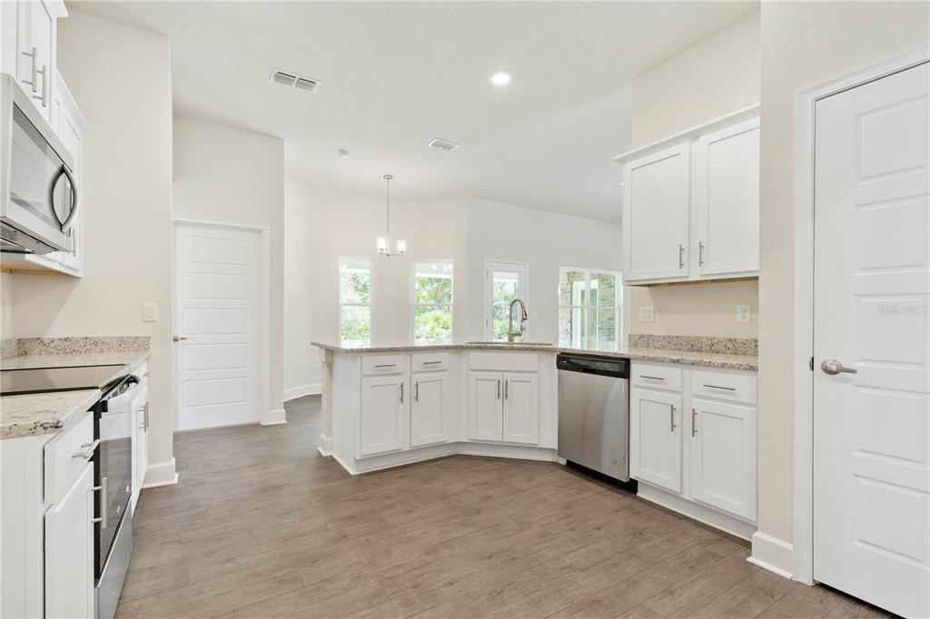 A kitchen with white cabinets, granite countertops, stainless steel appliances, and wood-look flooring — 338 UNDERWOOD TRAIL, PALM COAST, FL
