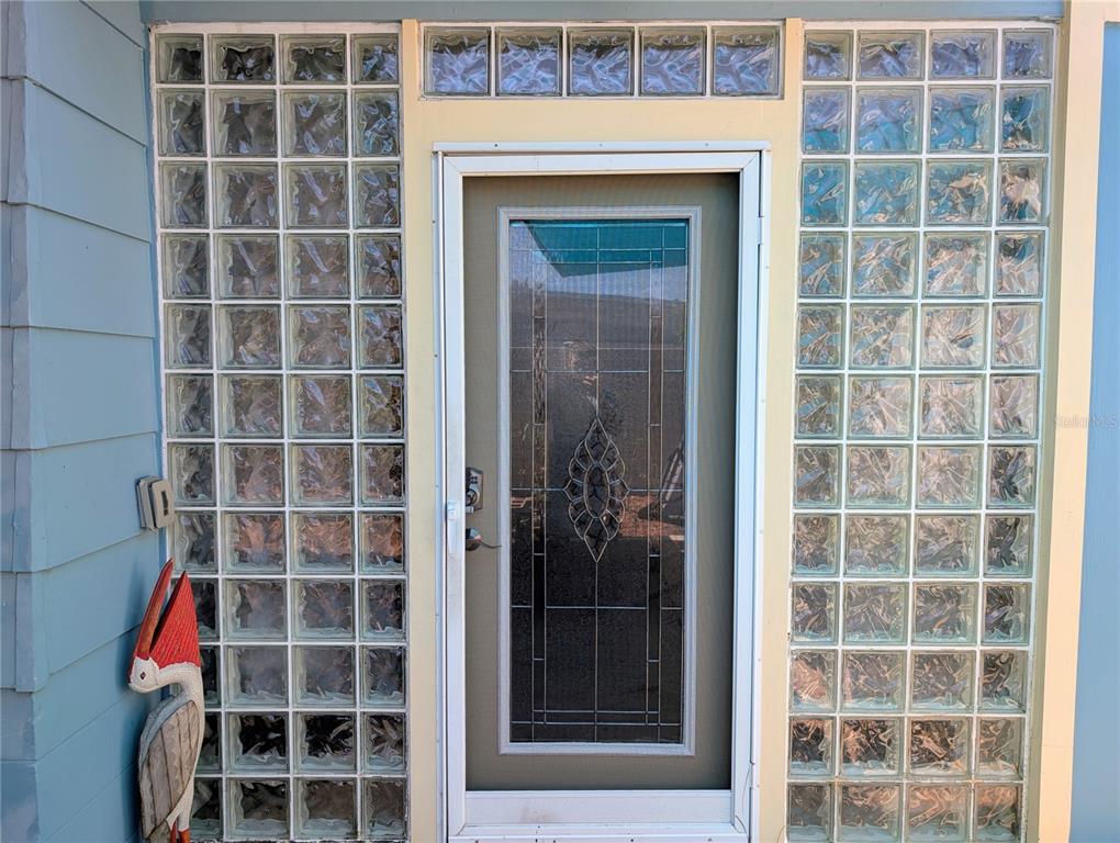 A room with tiled floors leads through an open doorway into a mirrored living area — 1519 CHANDLER AVENUE, CLEARWATER, FL