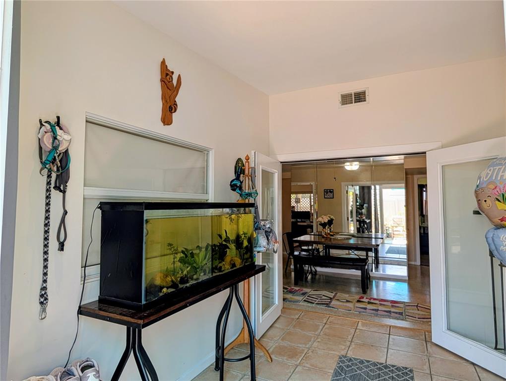 An entryway features a white front door flanked by glass block walls and tile flooring — 1519 CHANDLER AVENUE, CLEARWATER, FL