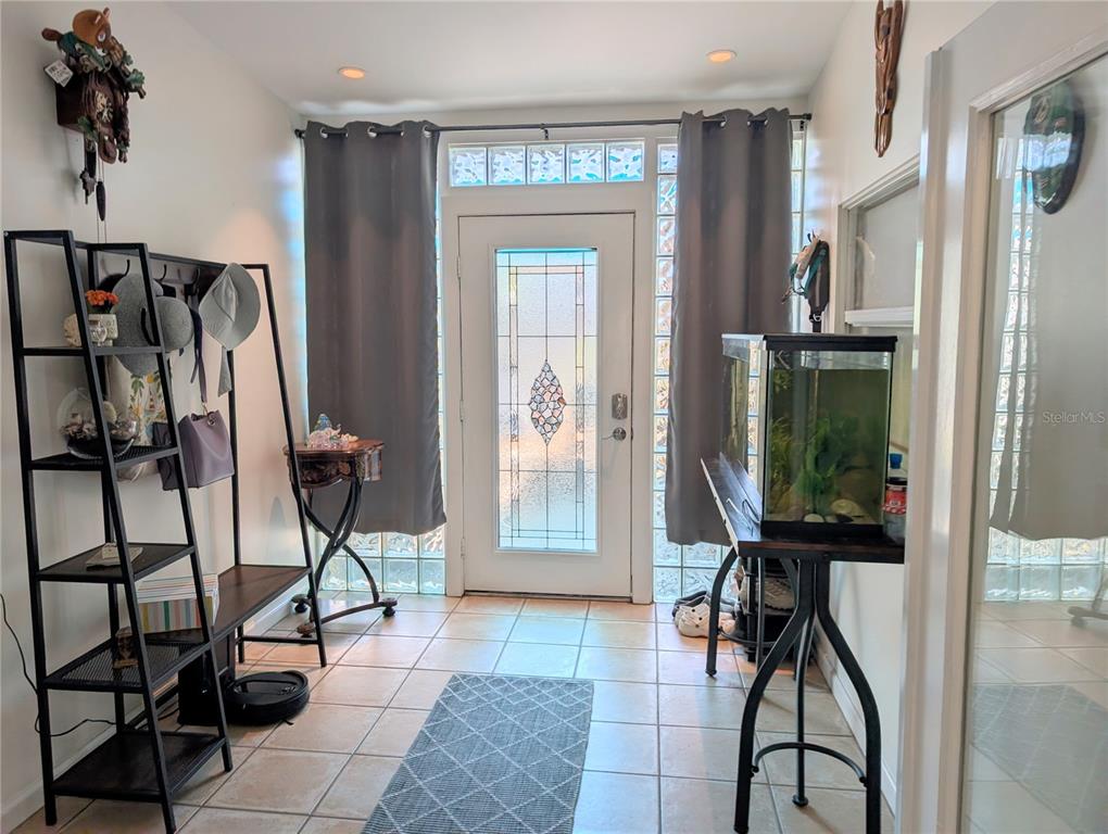 A sunroom features glass block walls, a wooden bench, two armchairs, and a central table — 1519 CHANDLER AVENUE, CLEARWATER, FL