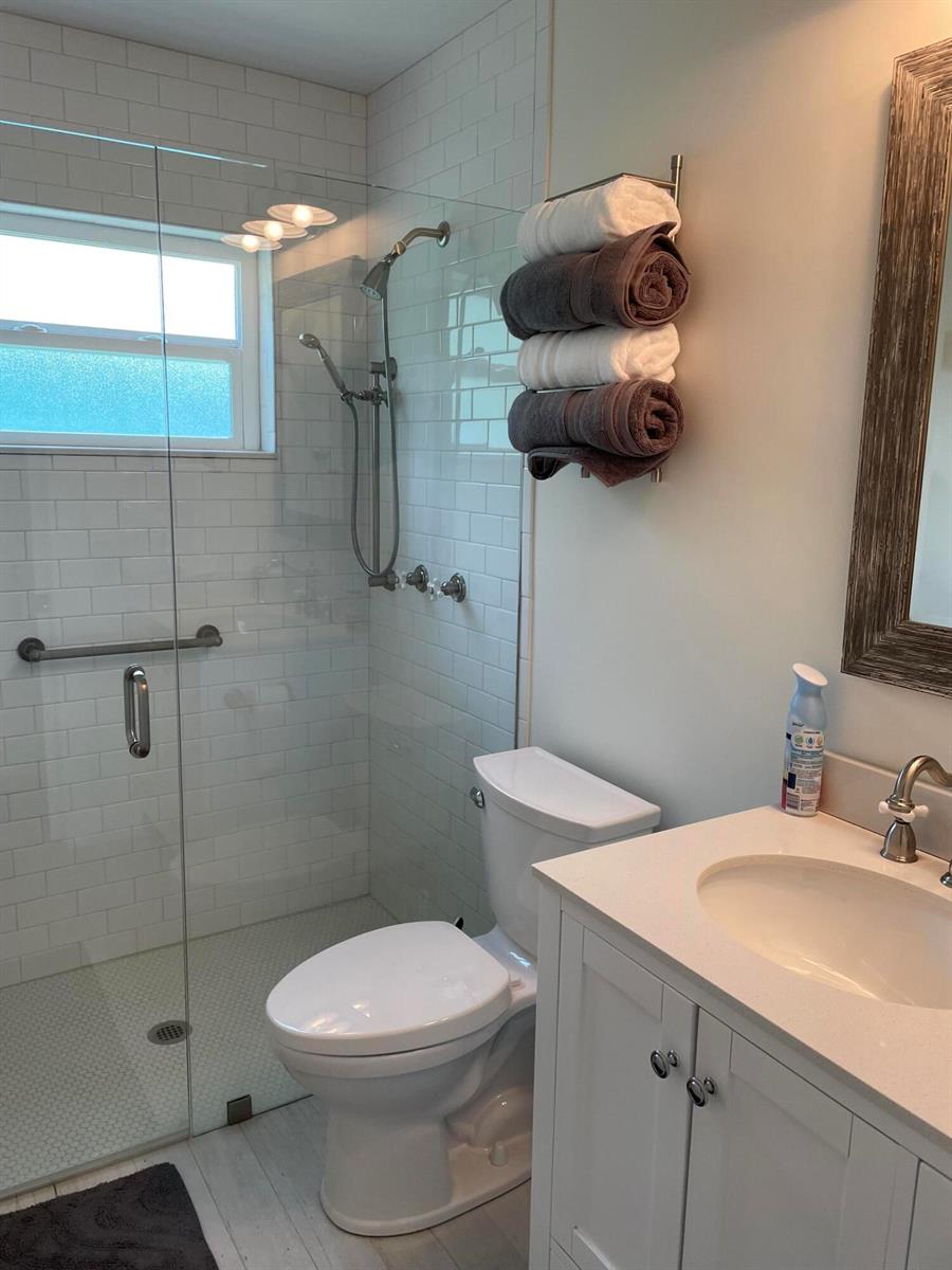 A bathroom features a glass-enclosed shower, a white vanity, a toilet, and wall-mounted towel storage — 1609 N M Street, FL 33460, FL