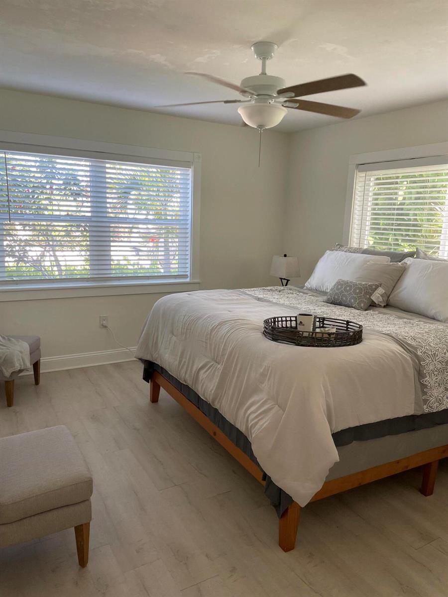 A bedroom features light wood-look flooring, a ceiling fan, and a bed with white bedding — 1609 N M Street, FL 33460, FL
