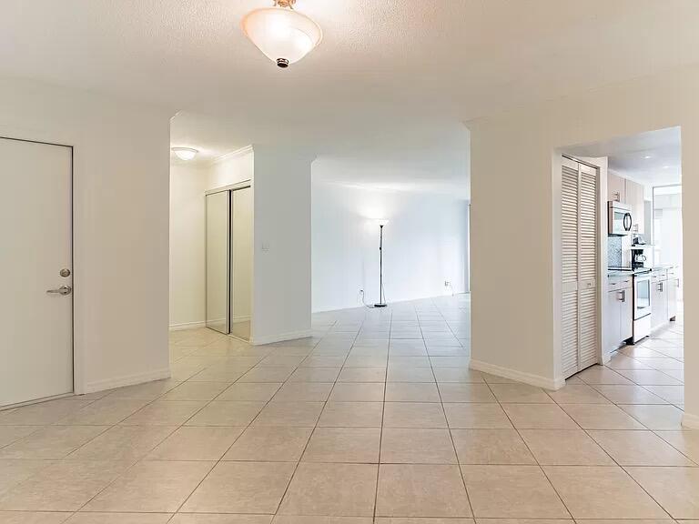 An open-concept living area features light-colored tile flooring, white walls, and a kitchen view — 6901 Cypress Road # C14, Plantation FL 33317, PLANTATION, FL