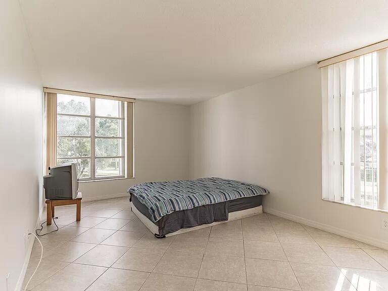 A bedroom with tile flooring, a bed, and a television on a small wooden stand — 6901 Cypress Road # C14, Plantation FL 33317, PLANTATION, FL