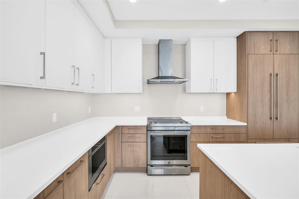 A modern kitchen features white upper cabinets, wood lower cabinets, stainless steel appliances, and countertops — 275 1ST AVENUE S UNIT 2708, ST PETERSBURG, FL