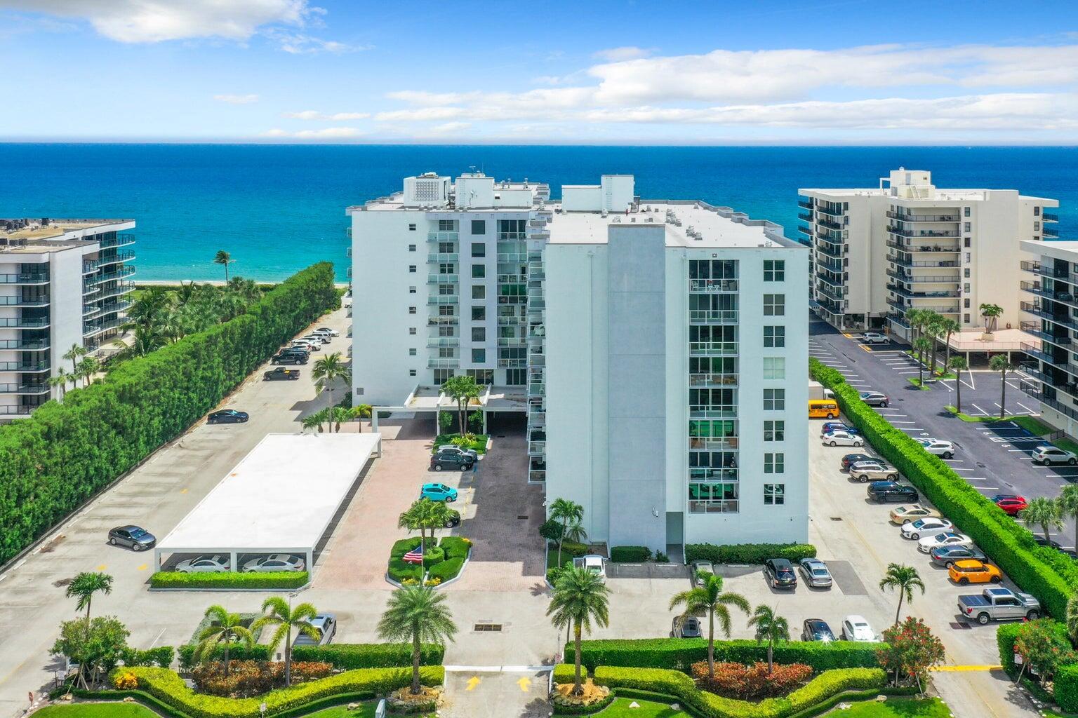 An aerial view of a white multi-story apartment building with parking lots and ocean views — 3450 S Ocean Boulevard # 406, Palm Beach FL 33480, PALM BEACH, FL